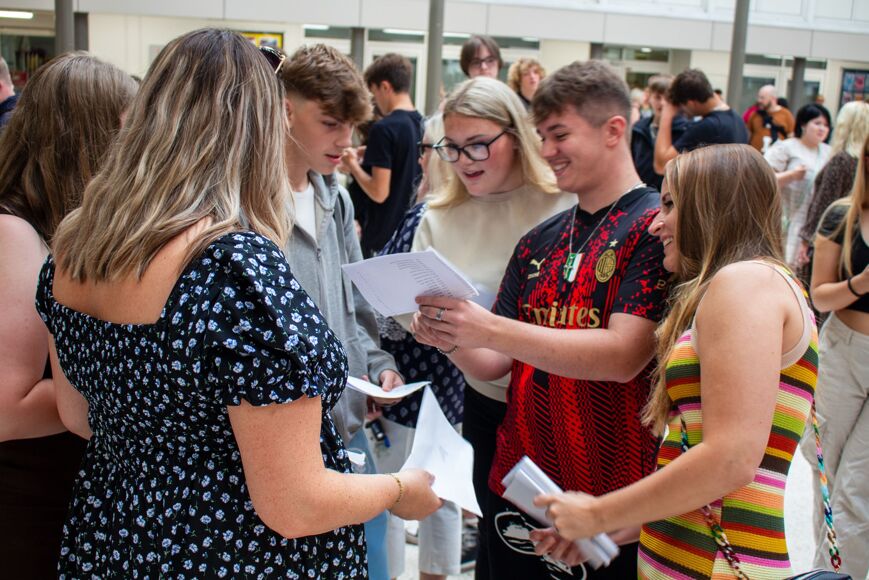 Group of students open their results with members of staff