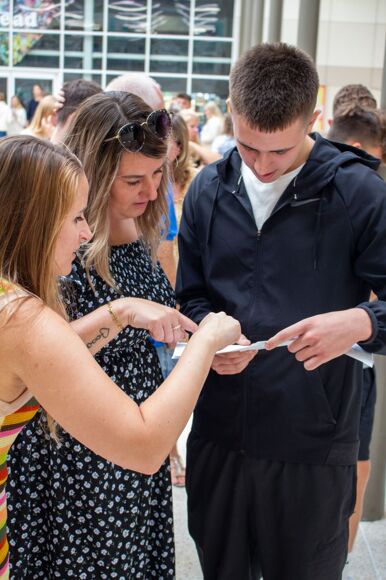 Male student looks at their GCSE results with Year Manager and Teacher